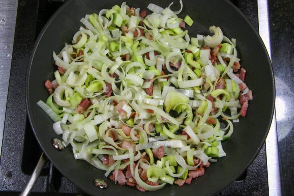 sautéed pancetta with uncooked leeks in skillet