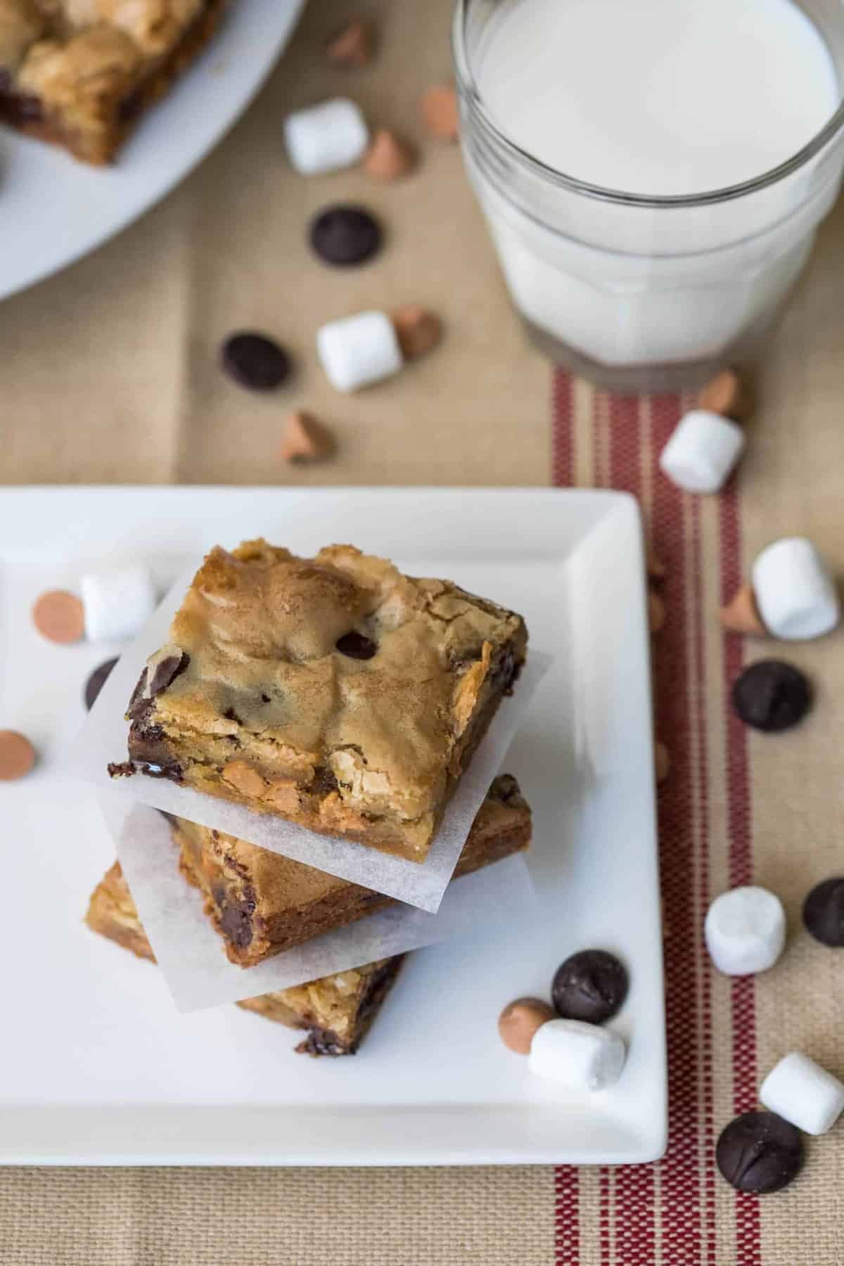 3 blondies stacked together next to glass of milk