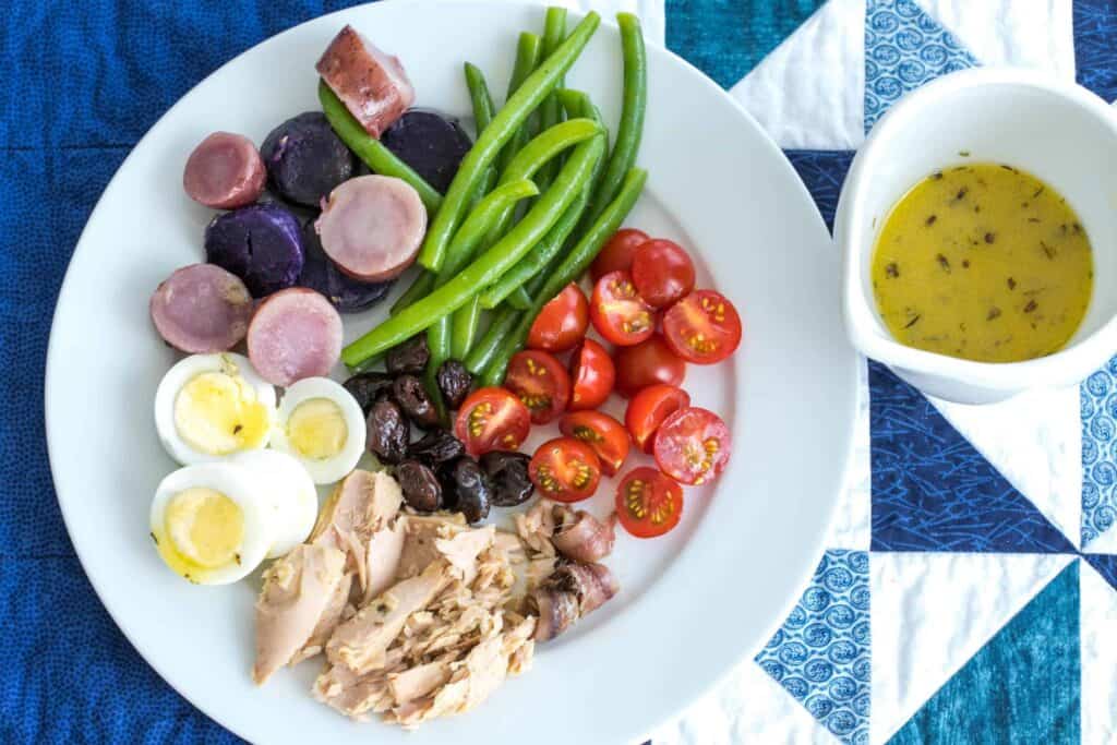nicoise salad with tuna, eggs, green beans, potatoes, olives, and cherry tomatoes