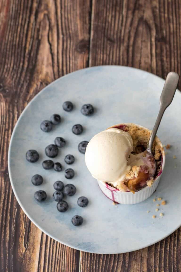 plate with blueberries and peach blueberry crumble with vanilla ice cream