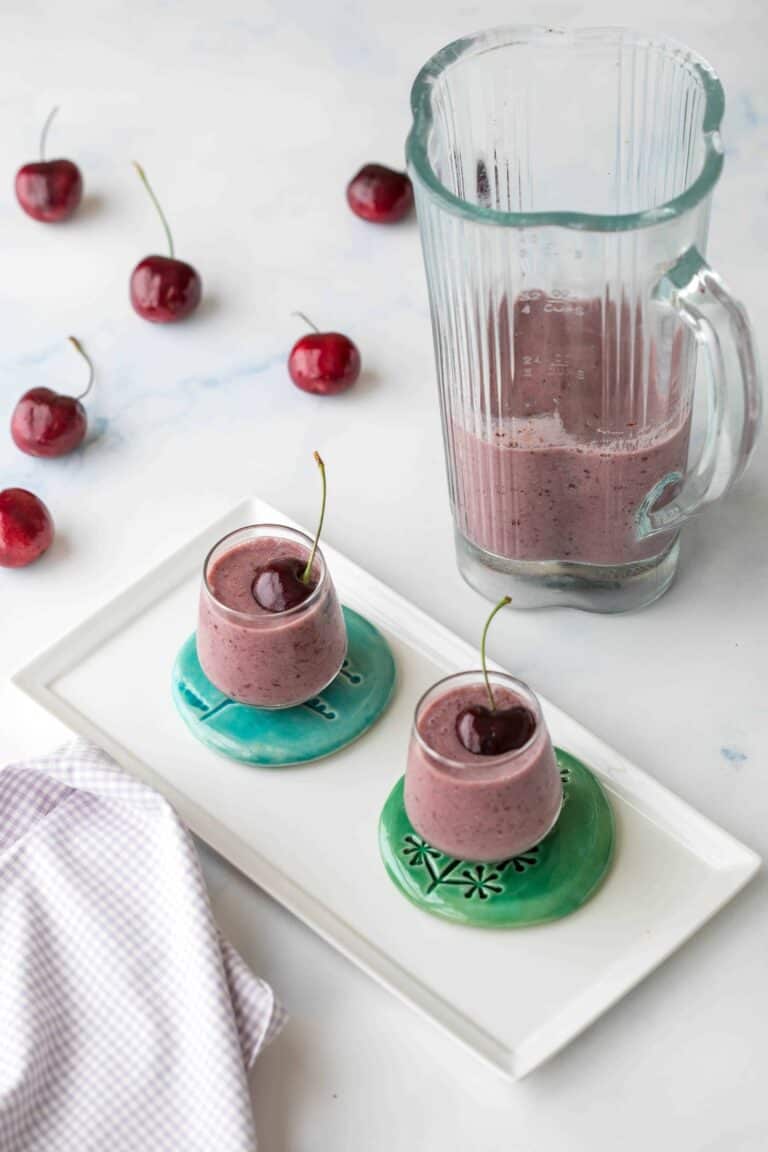cherry chia seed smoothies in shot glasses with blender, napkin, and cherries