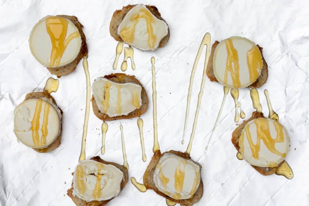 goat cheese toasts drizzled with honey on sheet pan