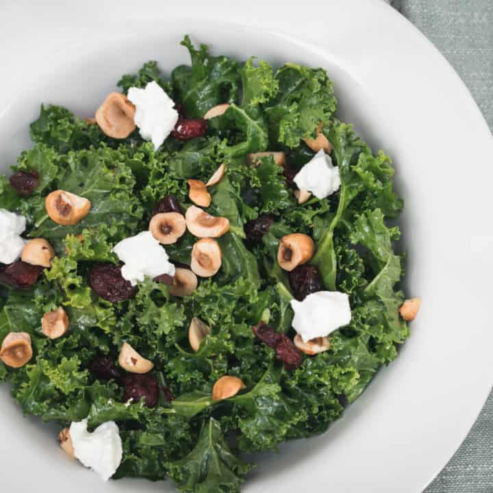 closeup of kale salad with cranberries, goat cheese, and hazelnuts