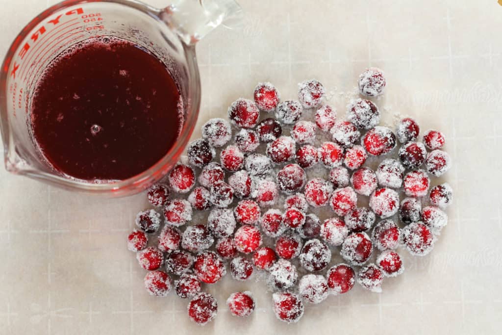 cranberry syrup next to sugared cranberries on parchment paper