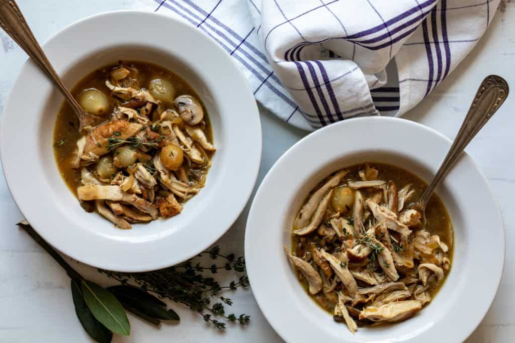 two bowls of coq au vin blanc with herbs and kitchen towel
