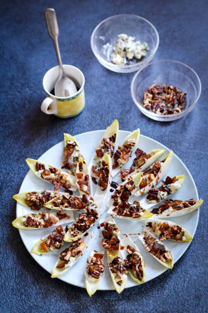 Endive appetizer with blue cheese and pecans with bowls of blue cheese and pecans and balsamic syrup