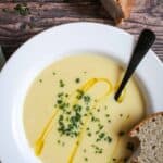 Bowl of vegan potato leek soup with crusty bread and chives