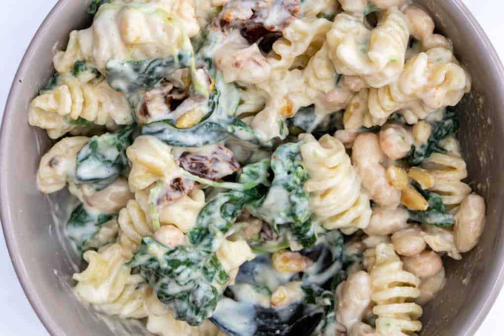 small bowl of creamy artichoke pasta with sun-dried tomatoes and spinach