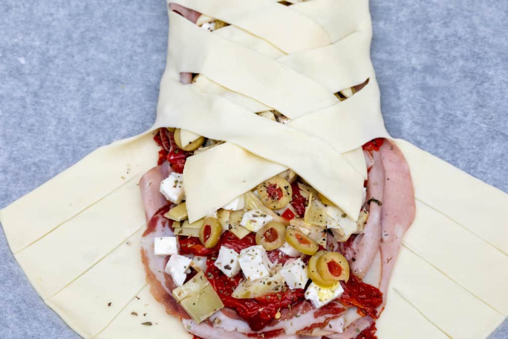 folding lattice of dough over filling for Antipasto Stromboli