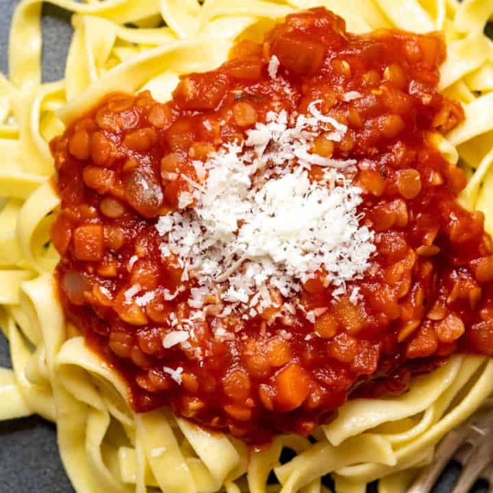 close up of red lentil bolognese sauce on fettuccine pasta