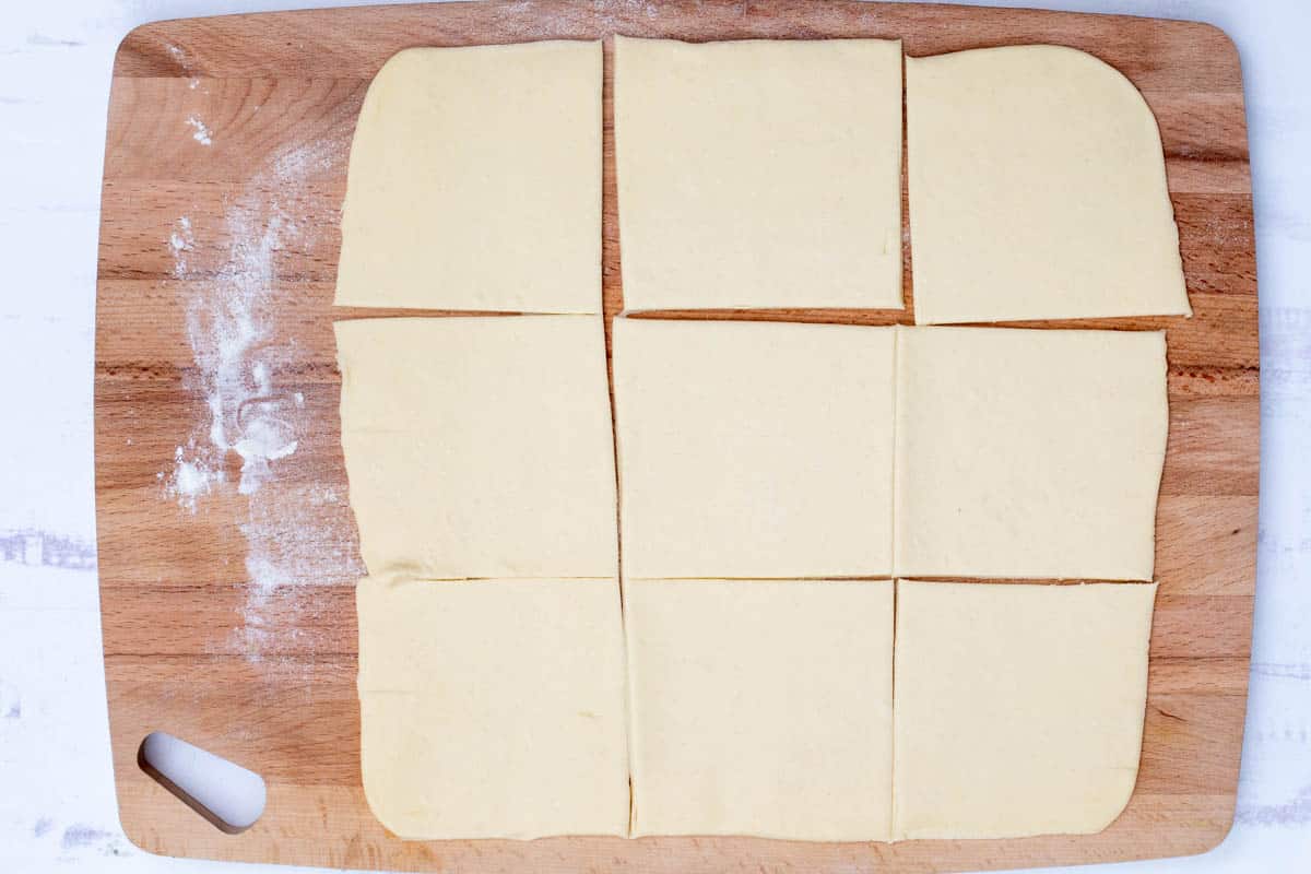 rolled out puff pastry dough on cutting board cut into 9 squares