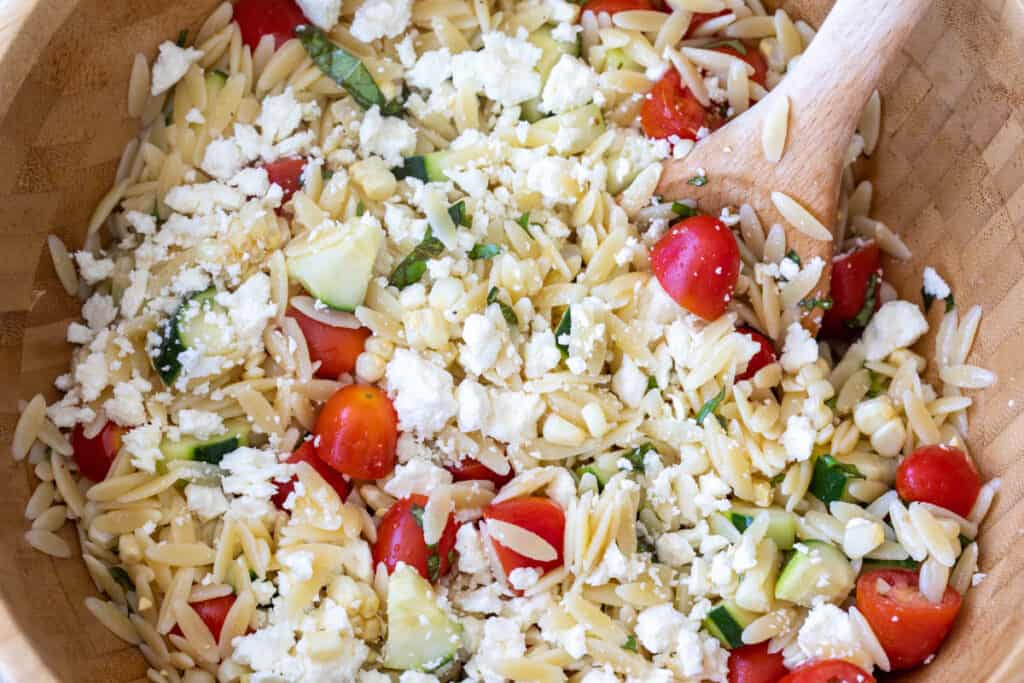closeup of summer orzo salad with cucumbers, tomato, corn, and feta