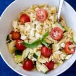 small bowl of summer orzo salad with tomatoes, feta, cucumbers, and basil