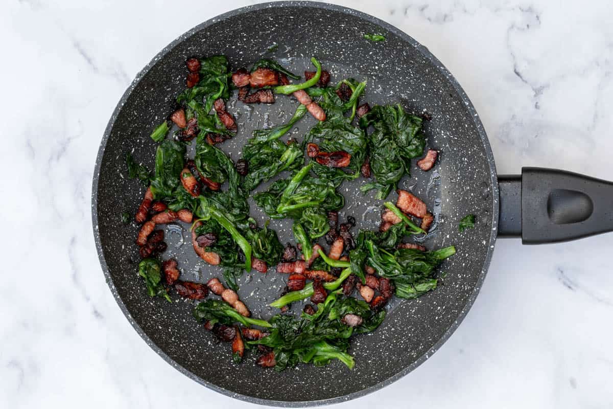 cooked bacon and spinach in skillet
