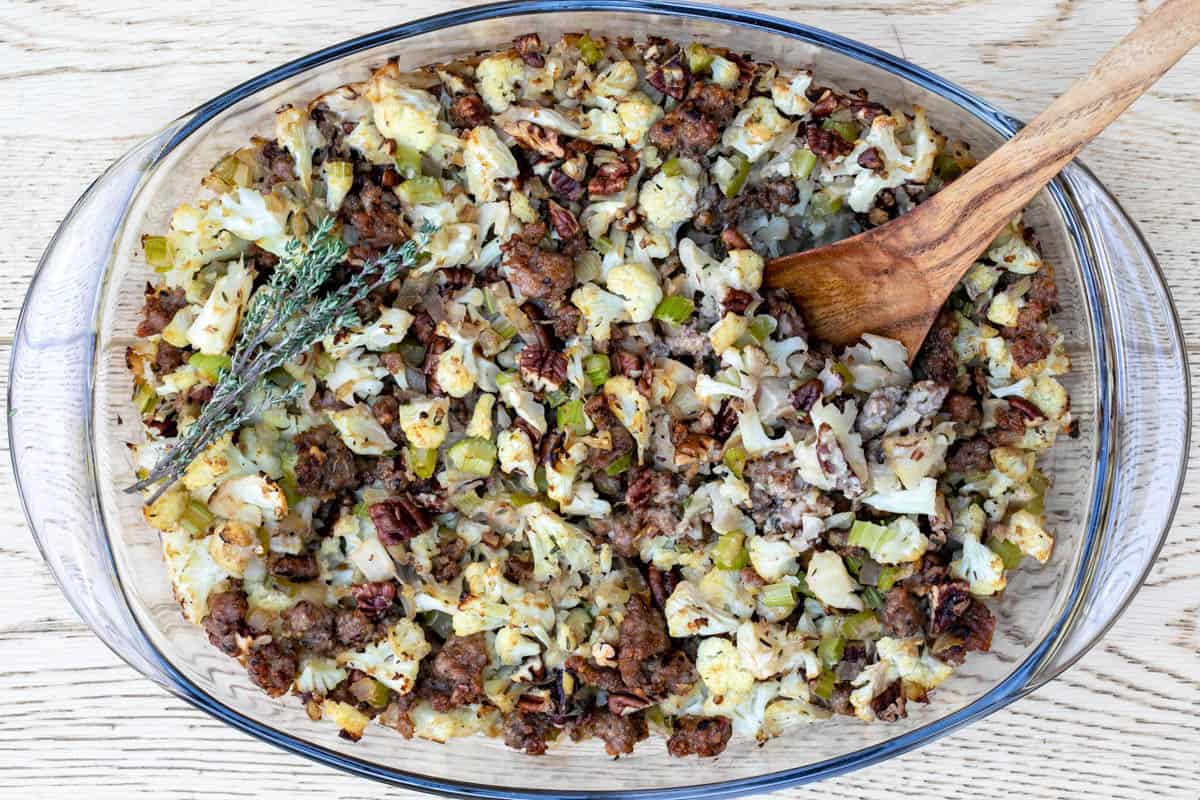 baked cauliflower stuffing in glass dish with wooden serving spoon