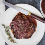 plate with pan-seared filet mignon with red wine sauce, knife, and thyme sprig