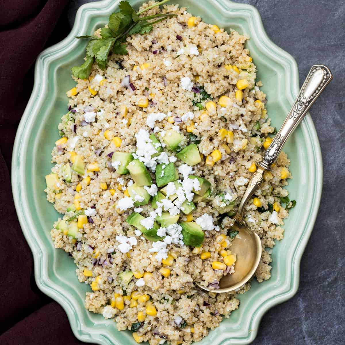 platter of quinoa avocado salad with corn with serving spoon