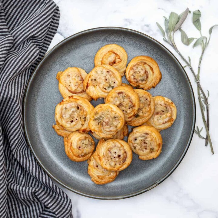 plate of puff pastry pinwheels next to fresh sage and napkin
