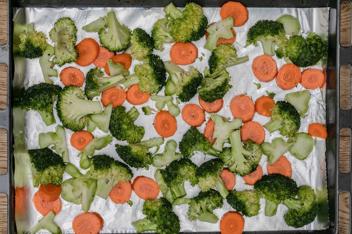 raw broccoli and carrots on sheet pan tossed with olive oil