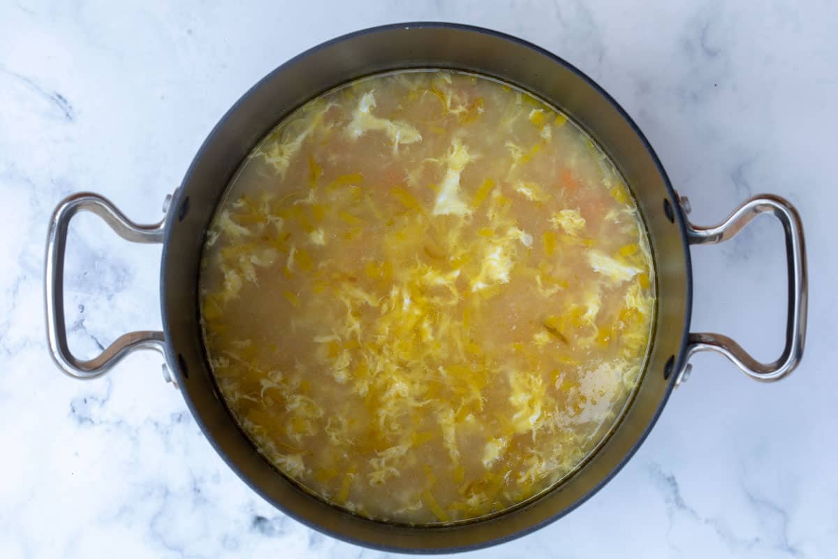 stockpot of chicken soup with rice and lemon after adding egg