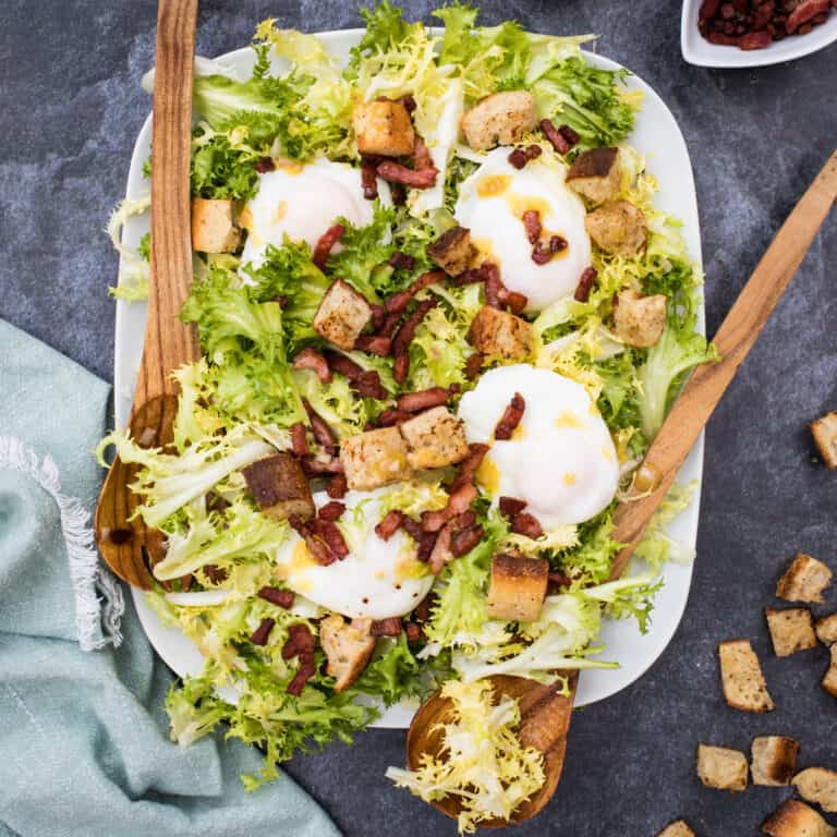 platter of frisee salad with serving utensils and napkin