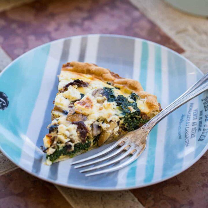 slice of spinach mushroom quiche on plate with fork