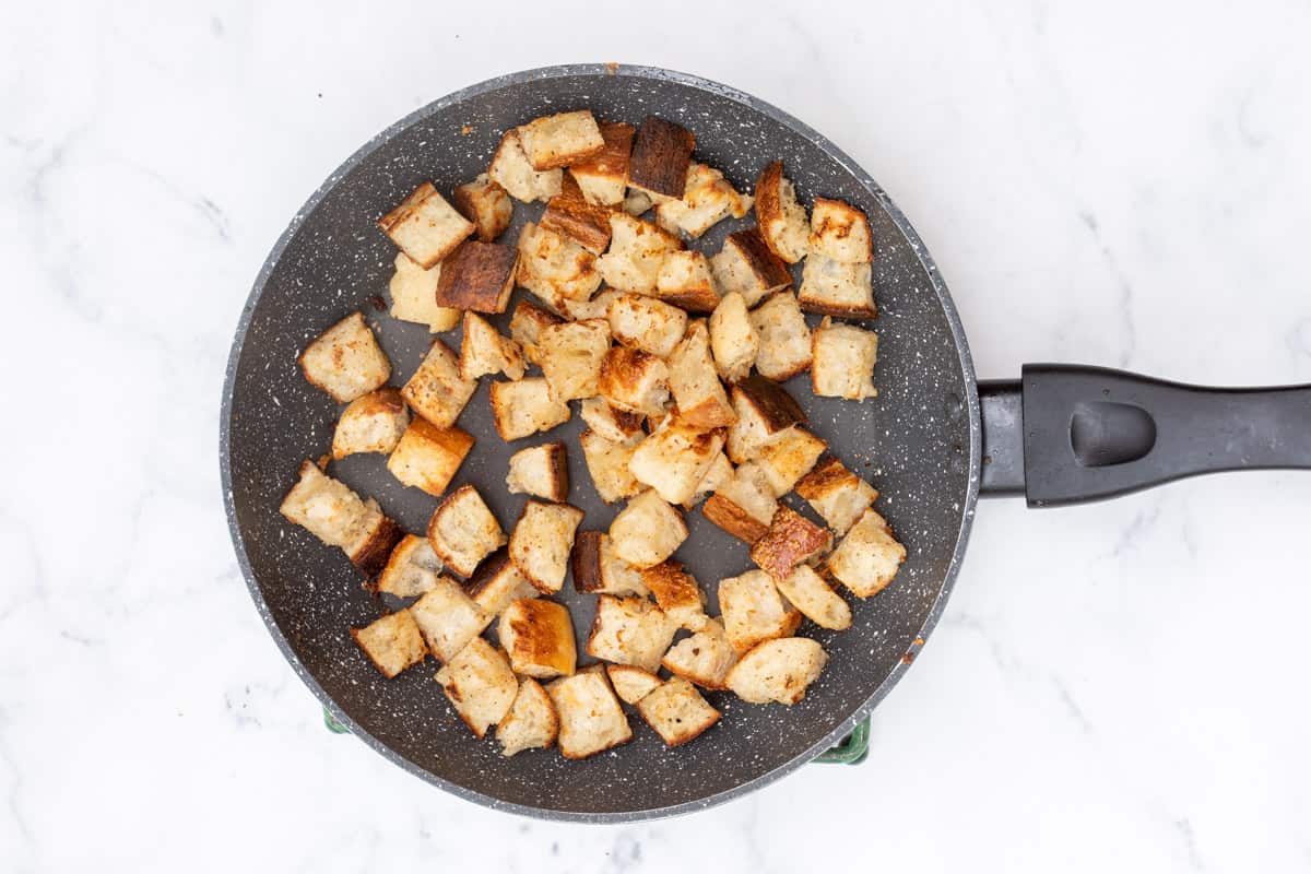 skillet with cubes of toasted baguette