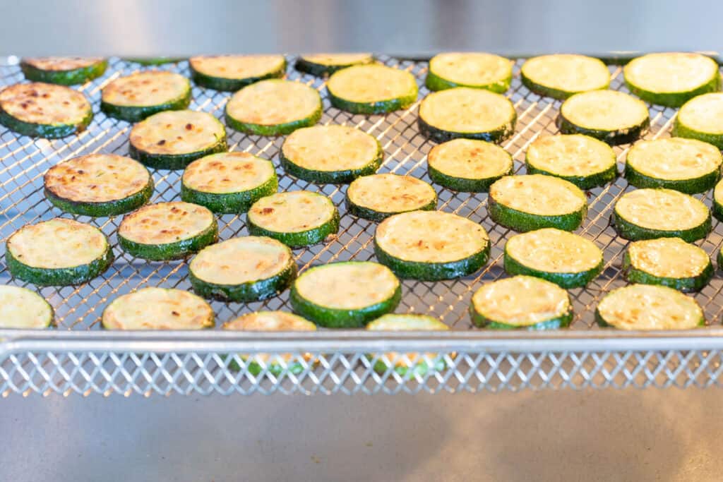 zucchini coins cooking on rack in air fryer