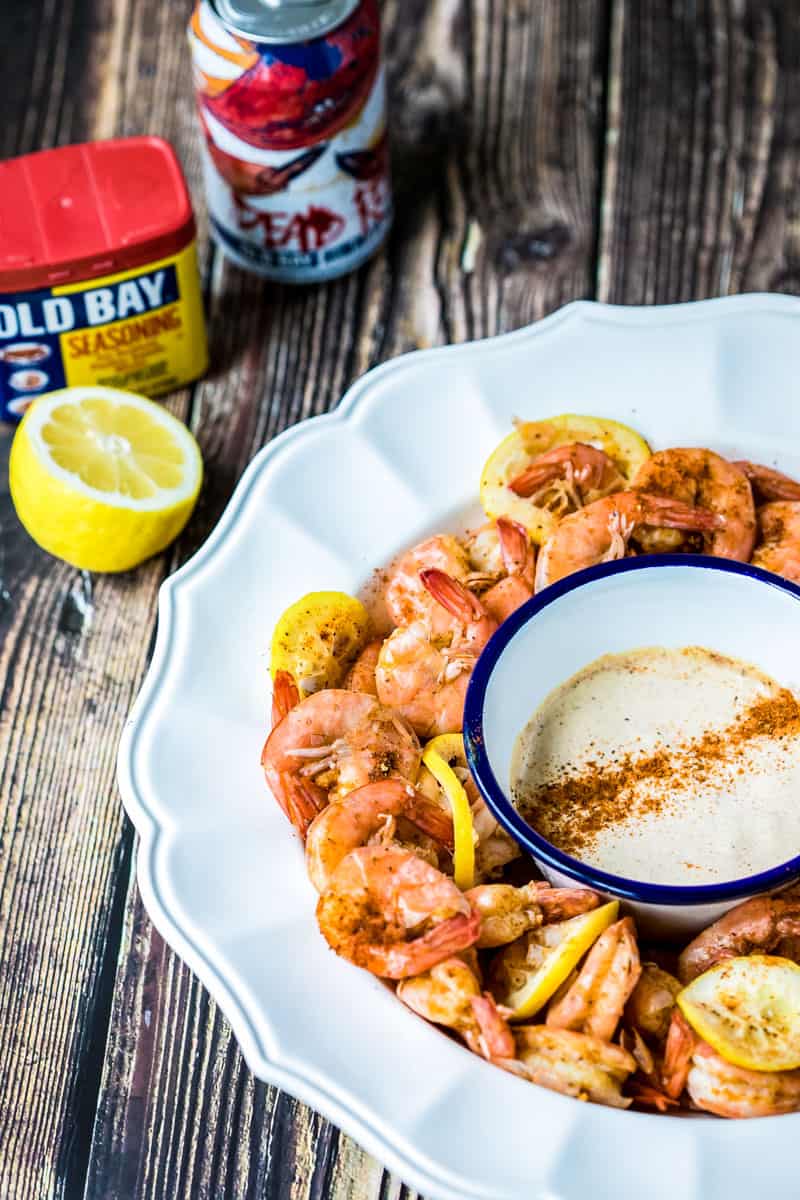 large bowl of Old Bay Spiced Shrimp with dip and lemon and jar of Old Bay Seasoning and beer
