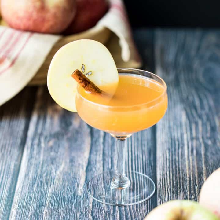 apple cider bourbon cocktail in front of basket of apples