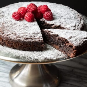 almond flour chocolate cake on cake stand with slice being removed