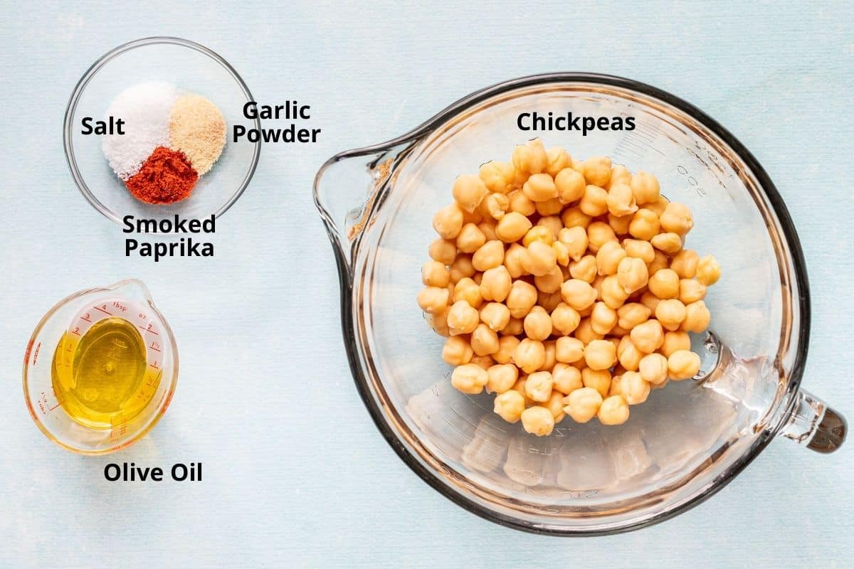 bowl of chickpeas next to small bowl of spices and small cup of olive oil