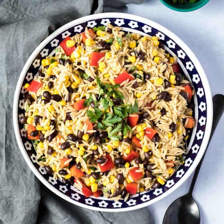 bowl of orzo pasta salad next to spoon and napkin