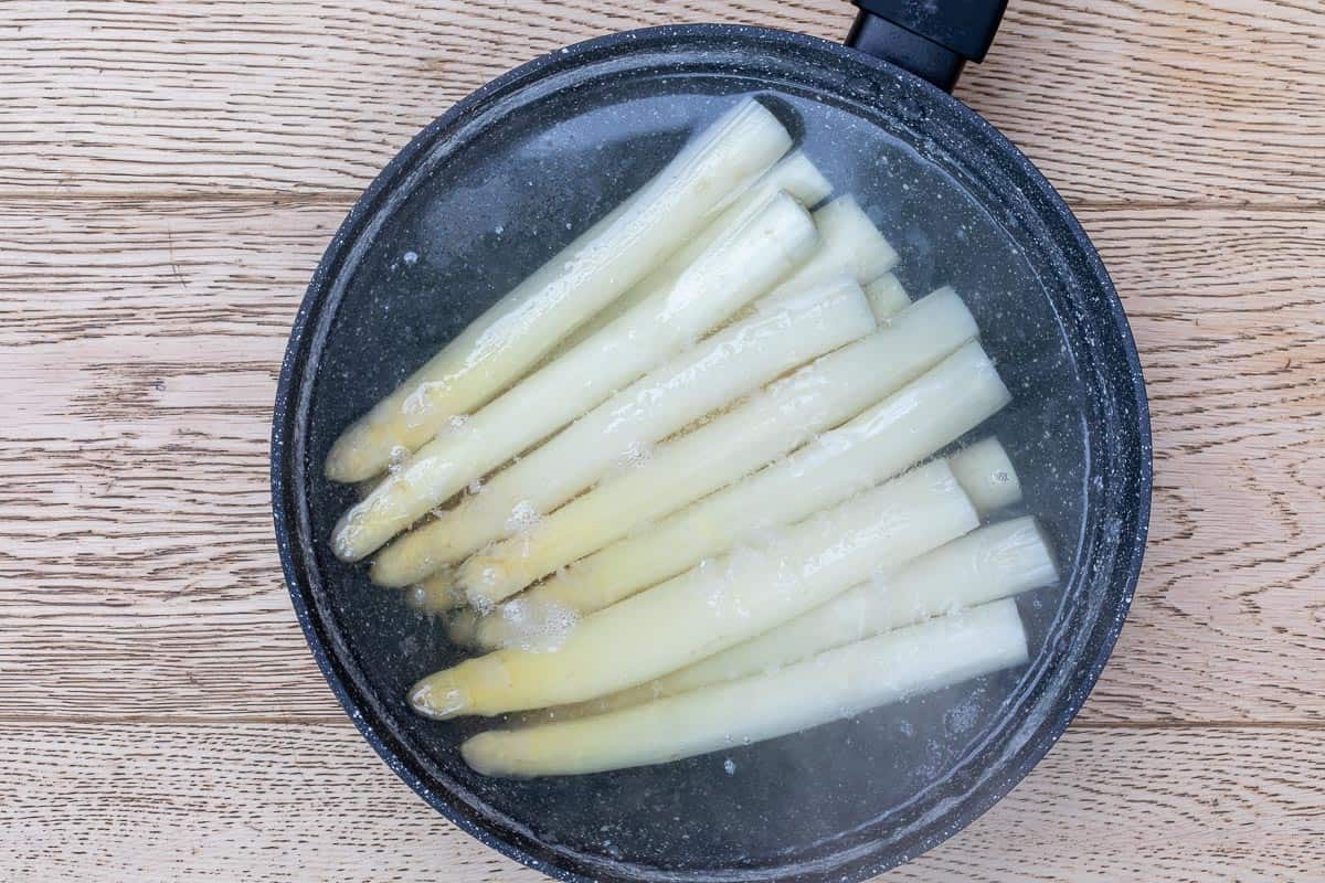 large skillet of white asparagus in boiling water