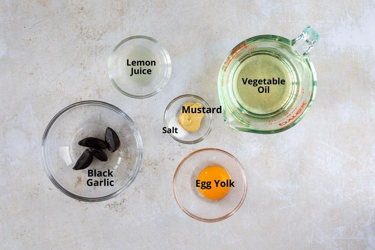 bowls of black garlic, egg yolk, lemon juice, salt, mustard, and vegetable oil