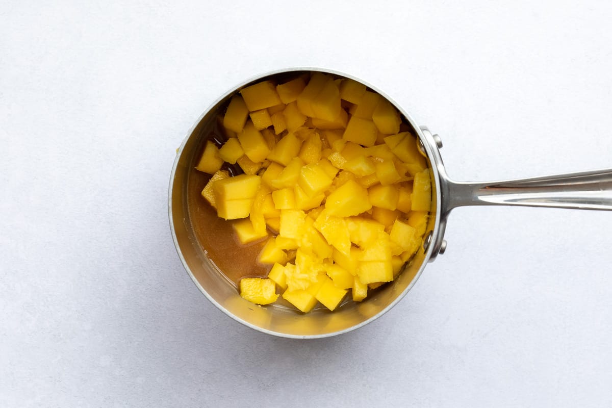 mango chunks and sugar in saucepan ready to cook