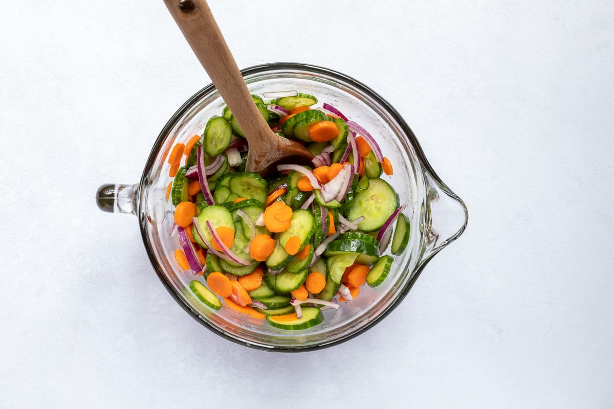cucumbers and carrots with red onion in glass bowl