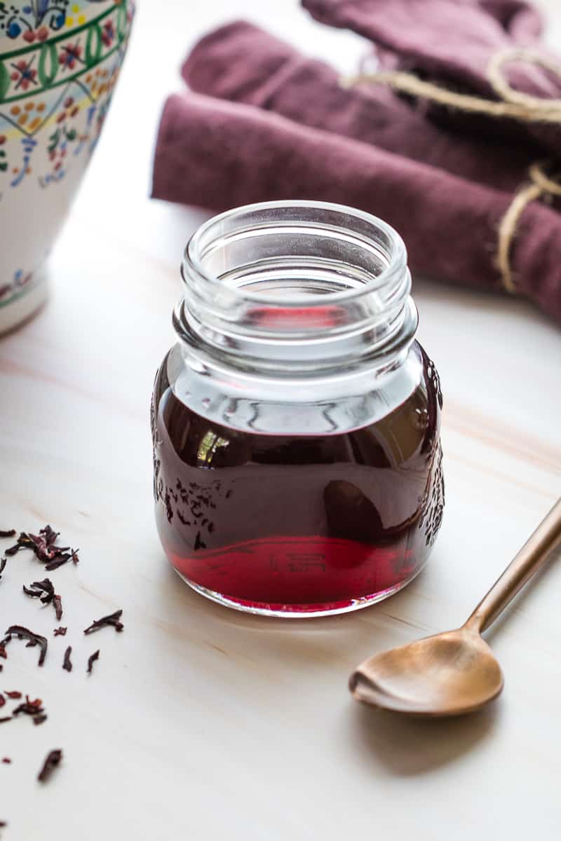 hibiscus syrup in jar next to spoon in front of napkins