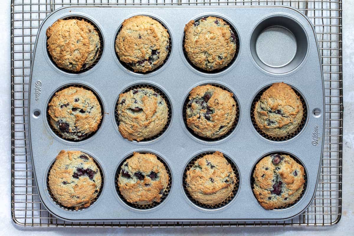 baked almond flour blackberry muffins in tin on rack