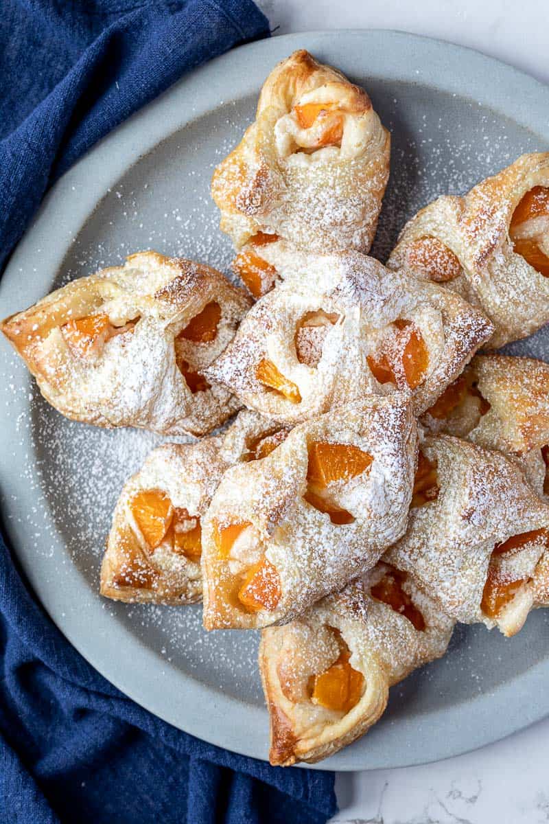 apricot danishes on round plate next to blue napkin