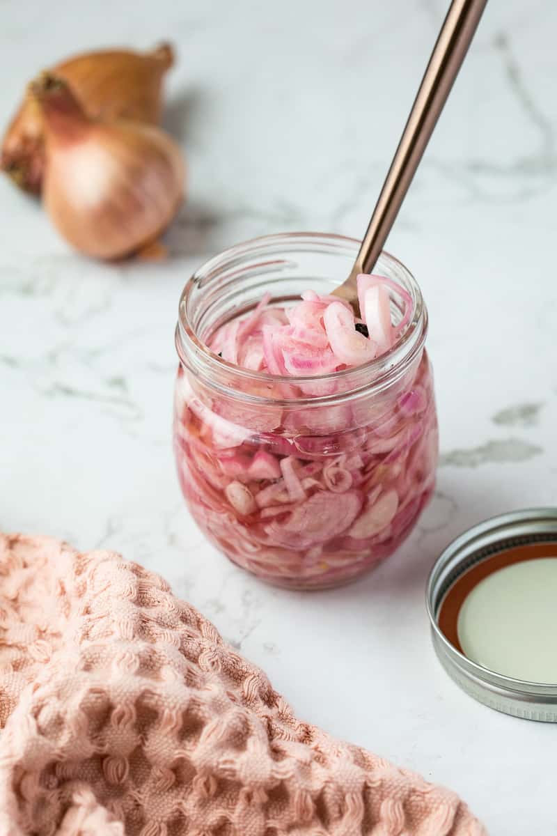 quick pickled shallots in jar next to napkin and shallots