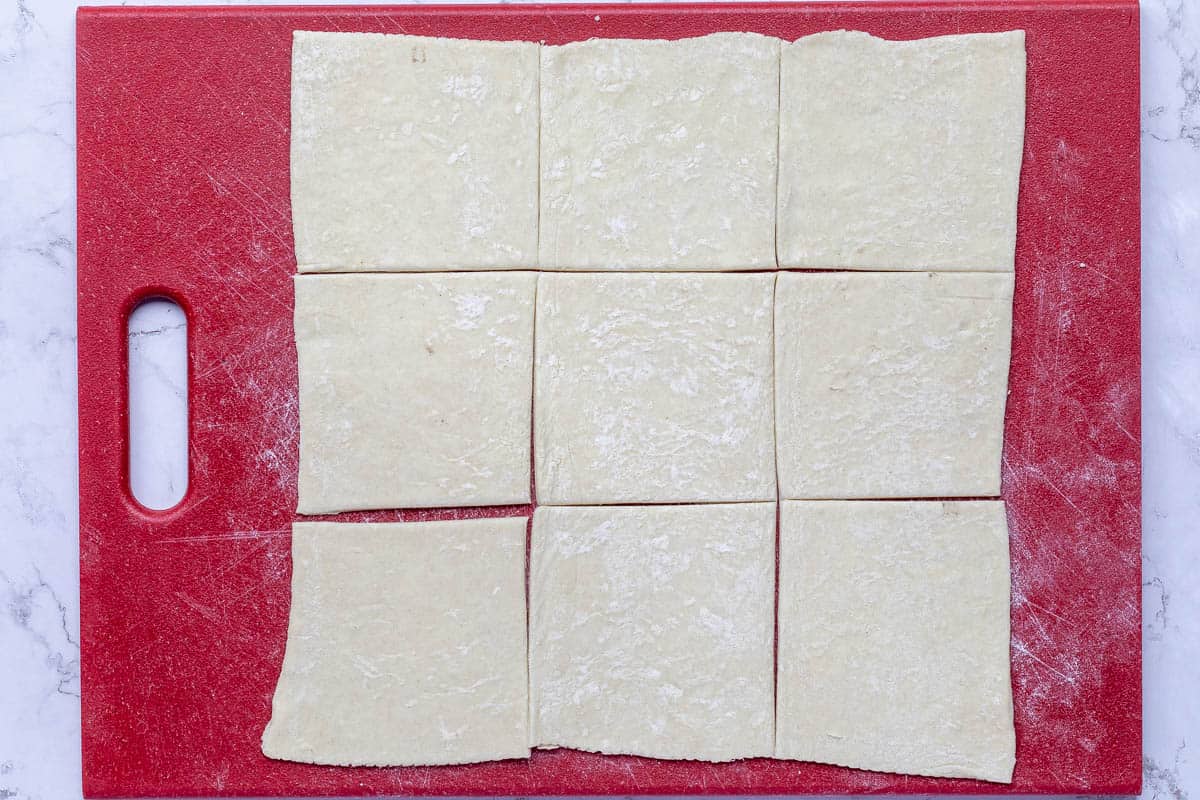 rolled out puff pastry dough cut into nine squares.