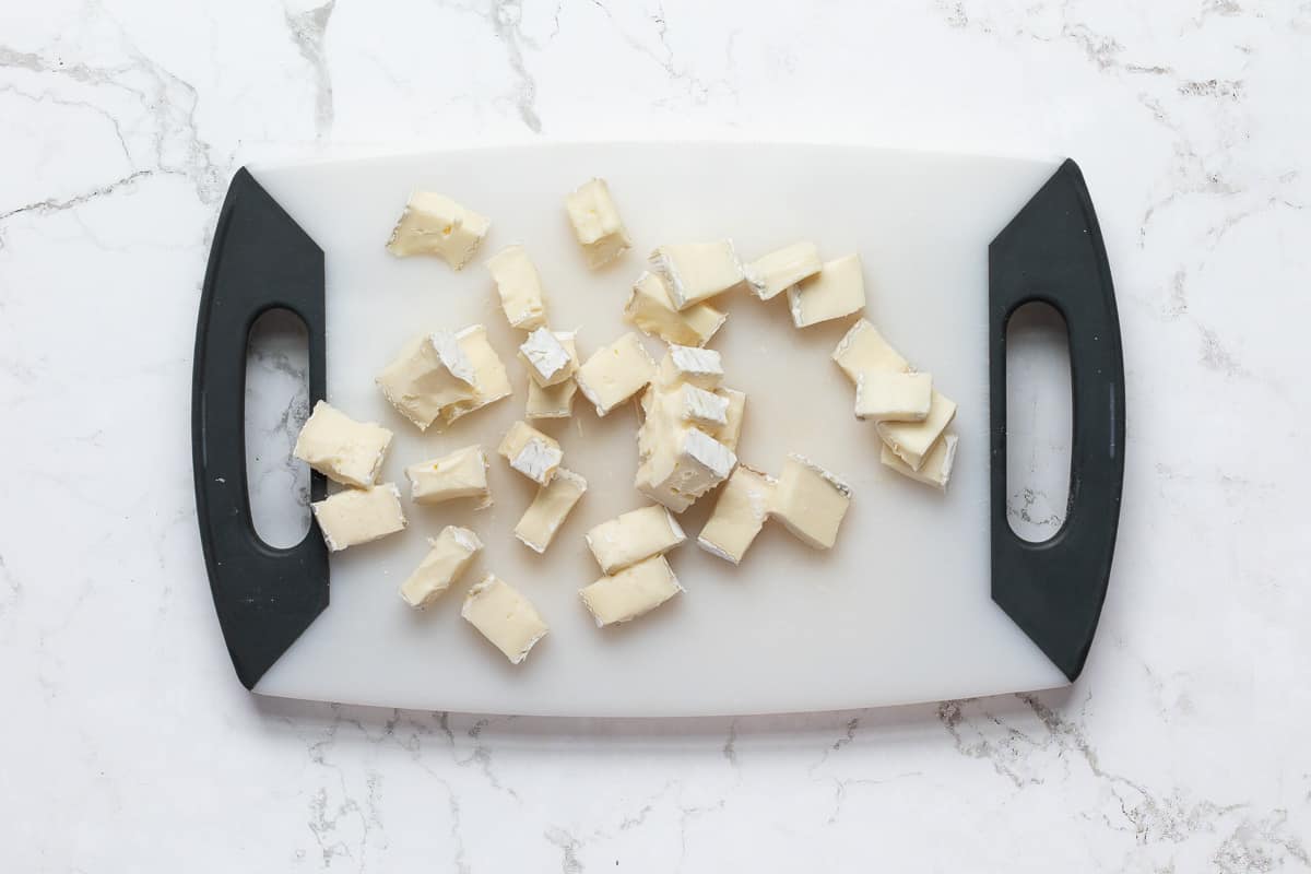 chopped brie cheese on small cutting board.