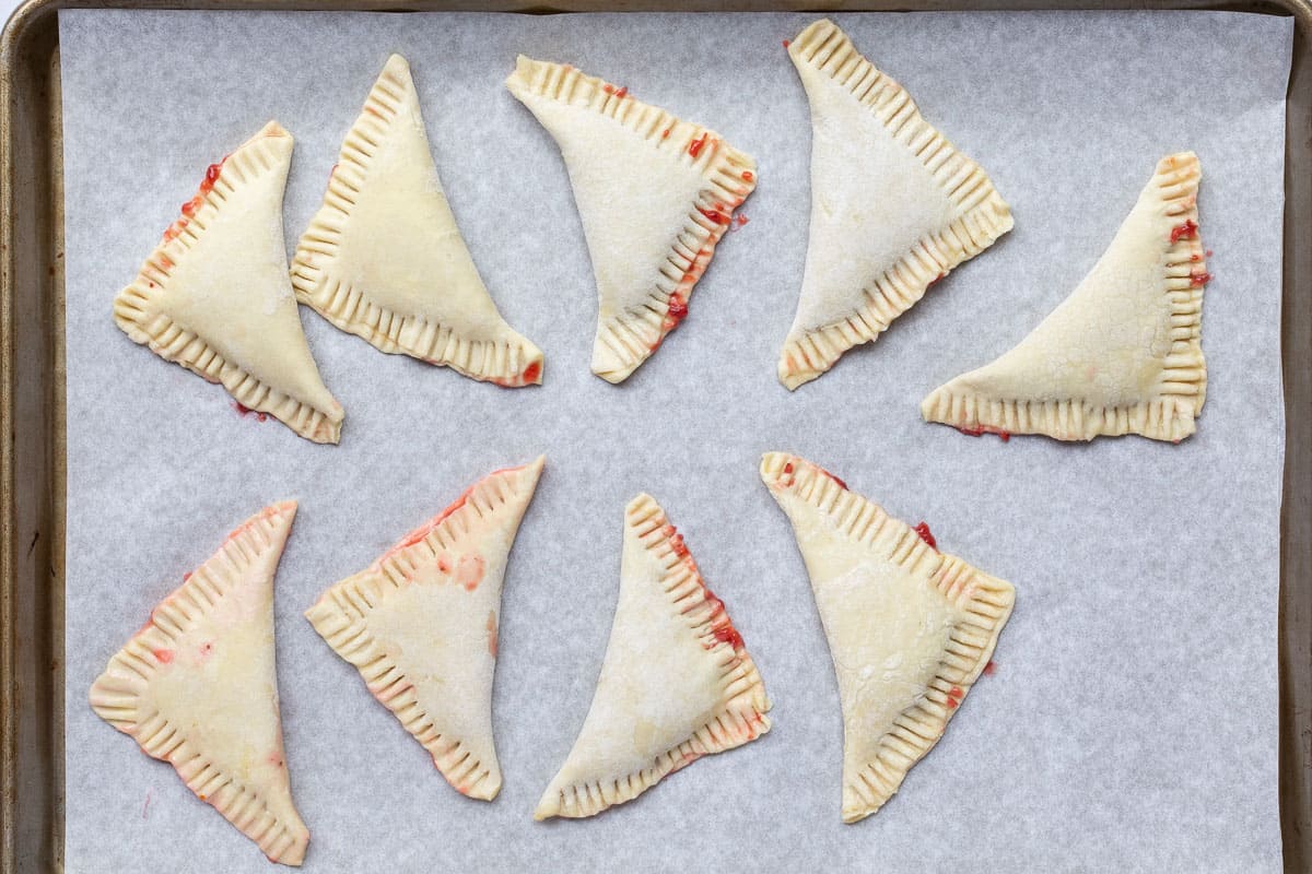 unbaked strawberry turnovers on parchment-lined sheet pan.