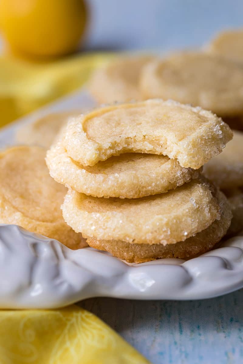 stack of lemon shortbread cookies on platter with yellow napkin.