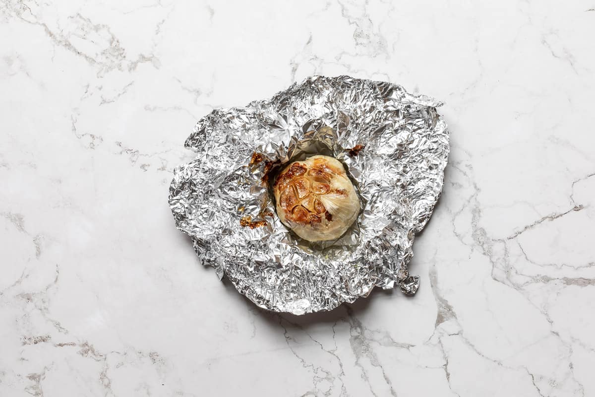 head of roasted garlic on bed of aluminum foil.