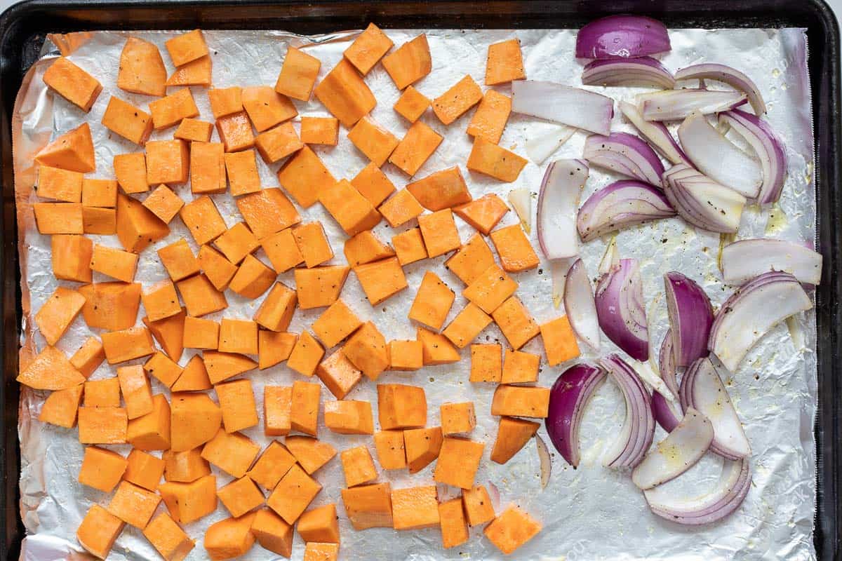 cubed sweet potatoes and red onion wedges on sheet pan.