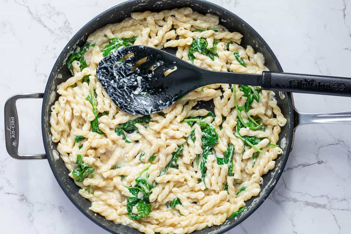 mascarpone pasta in skillet with spatula.