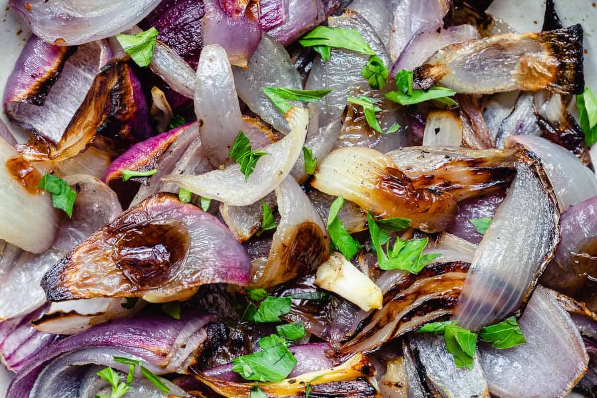close up image of roasted red onions with parsley.