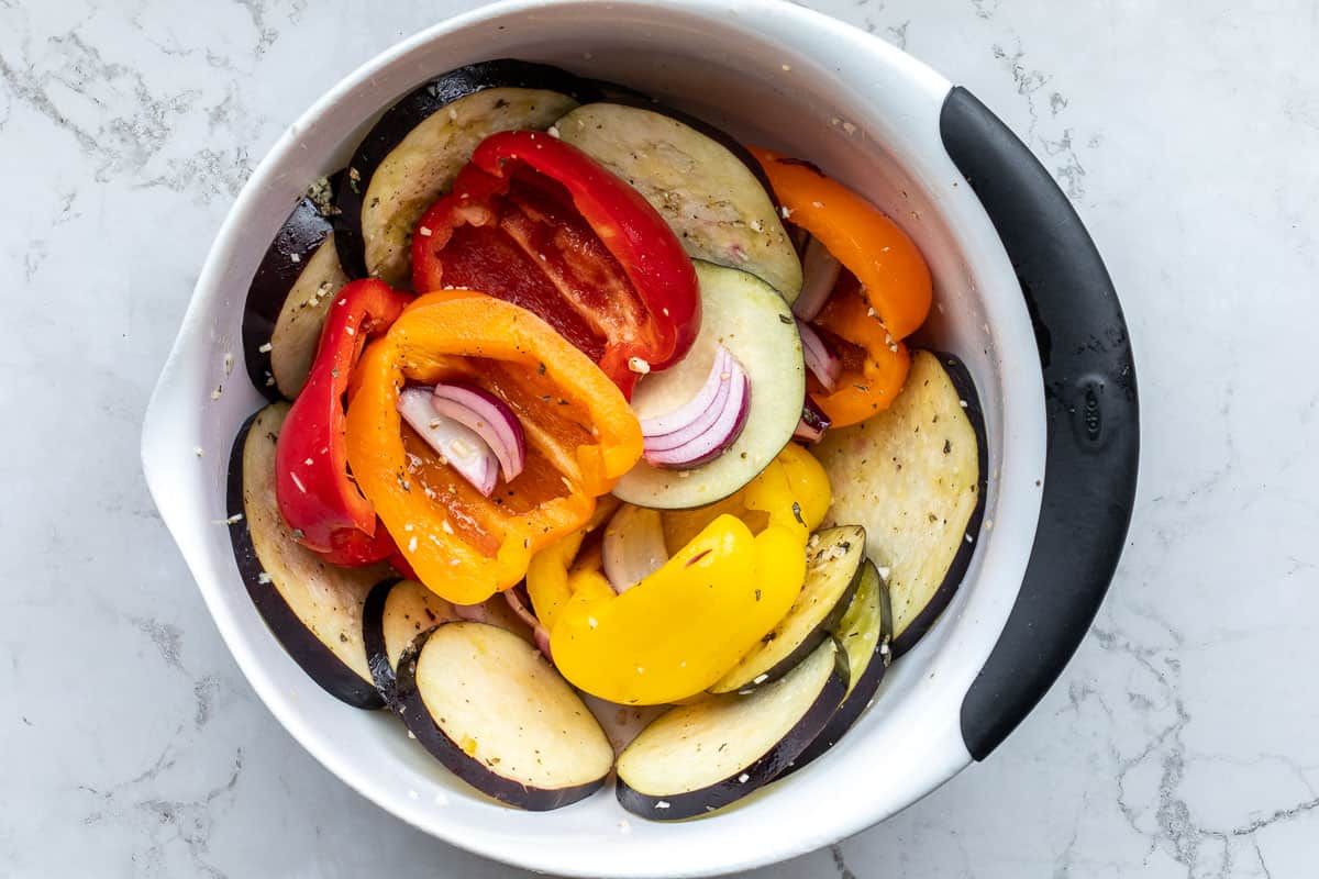 marinated onions, bell pepper halves, and eggplant slices in large mixing bowl.